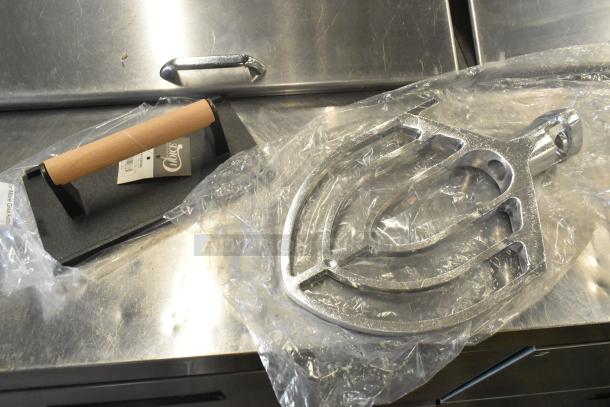 Brand new scratch and dent Choice 9" x 5" cast iron steak weight with wooden handle and commercial dough mixer paddle.