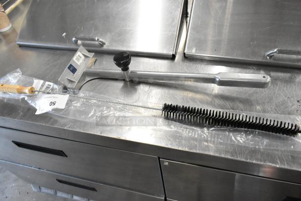 New scratch and dent SKU311731 wire cleaning brush and Redco 10025VK metal scraper, in packaging on metal surface.