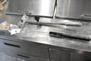 New scratch and dent SKU311731 wire cleaning brush and Redco 10025VK metal scraper, in packaging on metal surface.