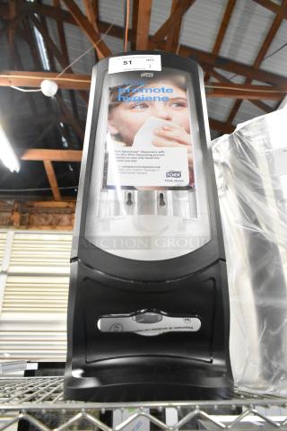 Brand new Tork black and clear poly napkin dispenser, visible promotional label, slight scratches, item no. 51.