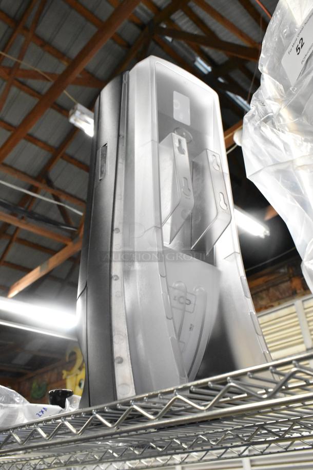 New Tork black and clear poly napkin dispenser, scratch and dent condition, displayed on a metal rack.