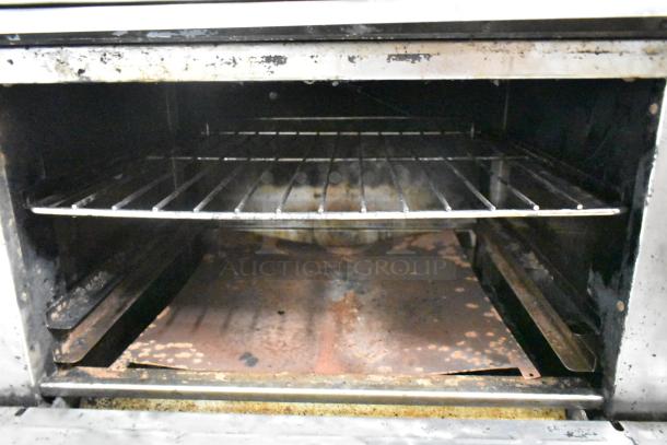 Radiance stainless steel 6-burner range oven interior, showing signs of wear with rust on the base and used rack.