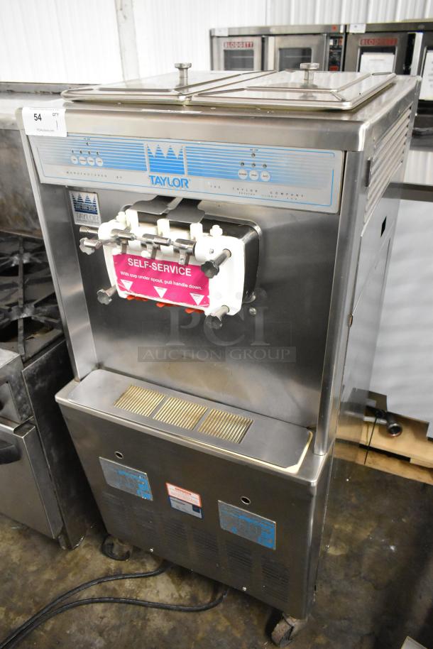 Taylor 339-27 stainless steel 2-flavor soft serve ice cream machine on casters, 208-230 volts, self-service label.
