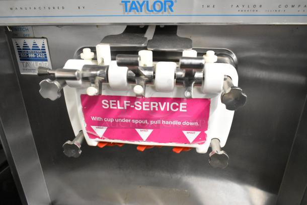 Taylor 339-27 stainless steel commercial soft serve ice cream machine; 2-flavor twist, on casters, self-service label visible.