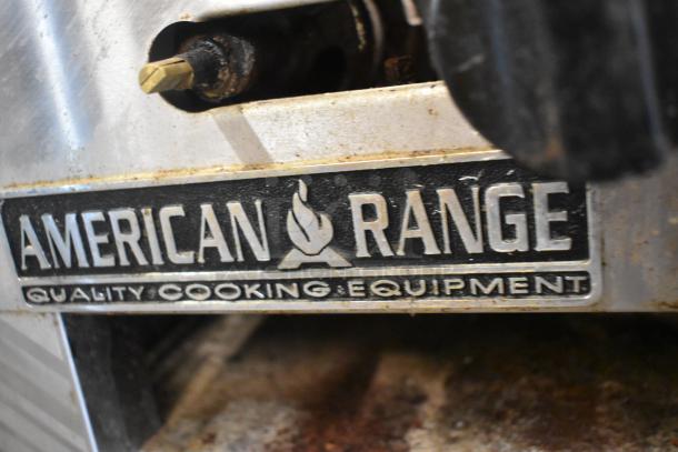 American Range stainless steel commercial gas burner, visible wear, branded "Quality Cooking Equipment."