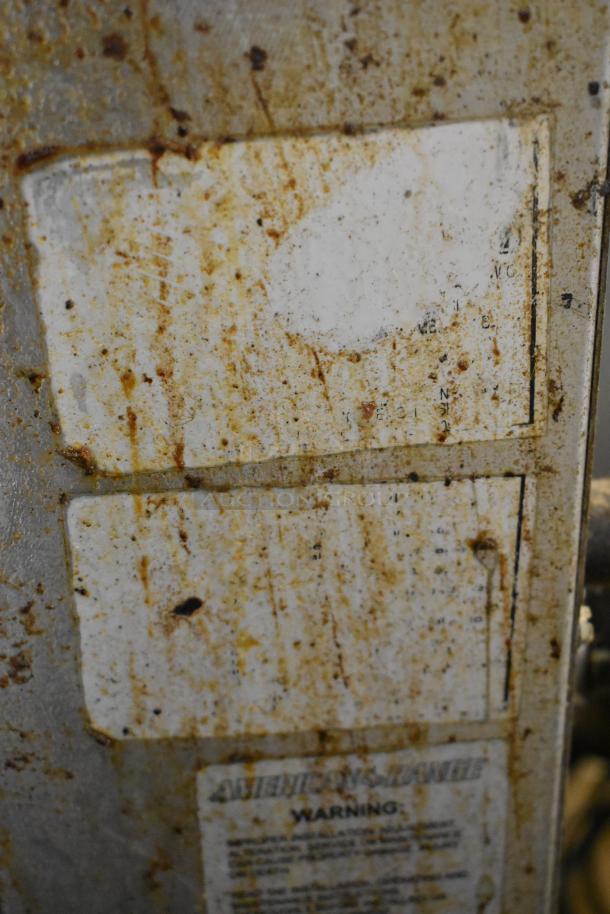 American Range stainless steel commercial gas burner, visible wear, rust stains on surface, warning label partially readable.