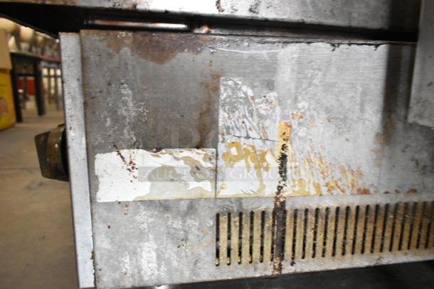 Copper Beech stainless steel gas charbroiler grill, visibly worn with rust and peeling surface, commercial-grade.