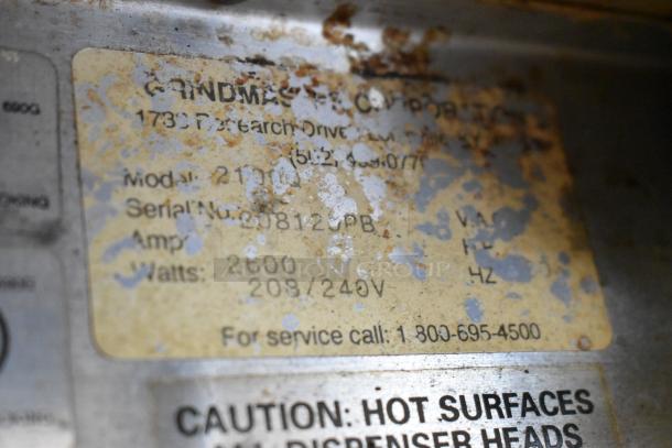 Grindmaster 2100Q model plate, showing model number, serial number, and electrical specifications. Worn condition, slightly rusted.