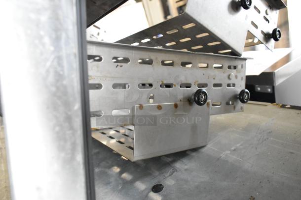 Stainless steel commercial drawer components for undercounter freezer. Shows metal construction, perforations, and roller wheels.