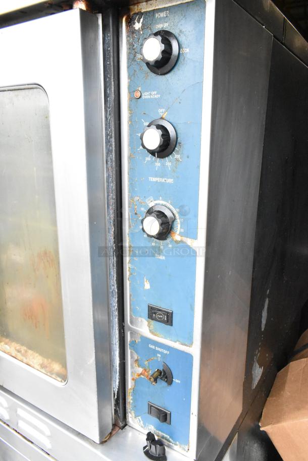 Duke stainless steel commercial gas convection oven with view-through doors, metal racks, thermostatic controls, and visible wear.