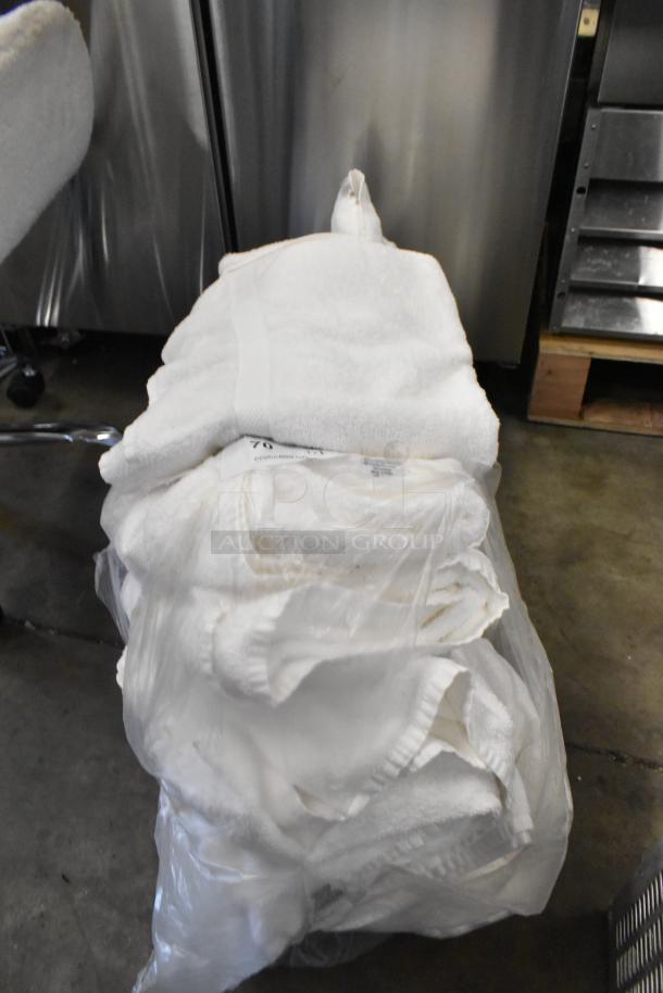 Lot of Golden Touch white towels in bulk packaging. Towels appear unused and neatly stacked in a transparent bag. Some tags visible.
