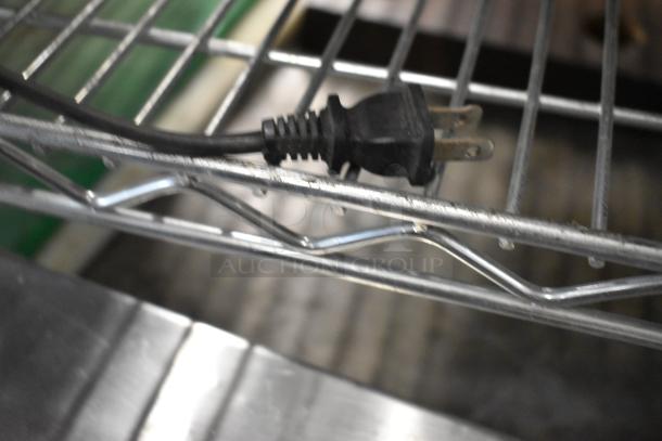 A close-up of a black electrical plug on a metal rack.