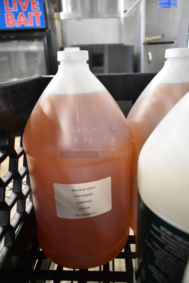 6 jugs including Malin & Goetz Peppermint Shampoo and Body Eclipse Body Lotion, 1-gallon each, in crate, brand labels visible.