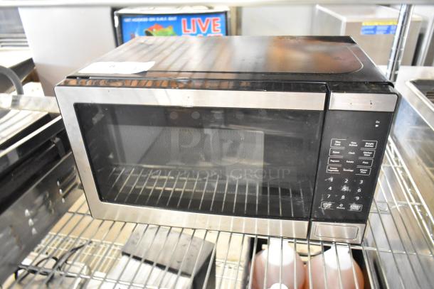 Walmart EM720C2WT-PM countertop microwave, stainless steel, 120 volts, keypads intact. Some surface wear visible.