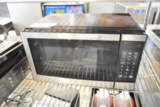 Walmart EM720C2WT-PM countertop microwave, stainless steel, 120 volts, keypads intact. Some surface wear visible.