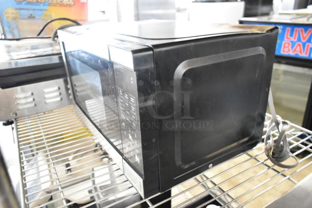 Walmart EM720C2WT-PM black countertop microwave oven with control panel, 120 volts, 1 phase, on metal rack.
