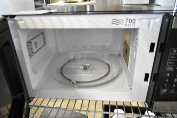 Walmart EM720C2WT-PM countertop microwave oven, 700 watts, with plate. Visible 120 volts, 1 phase label. Interior view.