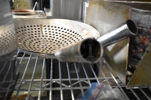 Lot of various kitchen items on a metal shelf, including a perforated round tray and ice scoop, used condition.