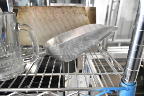 Lot of various items including a clear glass mug and a metal ice scoop on a metal rack, showing some wear.