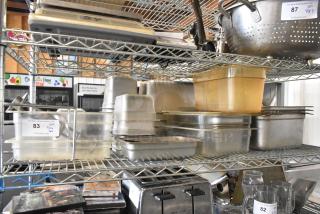 Tier lot of poly and stainless steel drop-in bins on metal shelving, including various kitchen items. Auction tags visible.