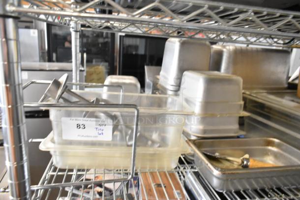 Various poly and stainless steel drop-in bins on metal shelves; includes utensils. Tag shows auction lot number 83.
