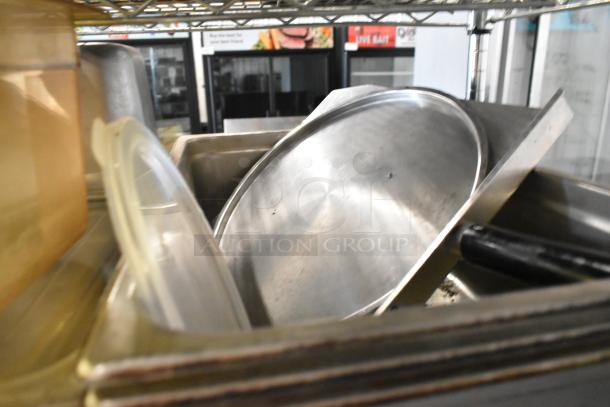Tier lot of poly and stainless steel drop-in bins in used condition on a metal shelf.