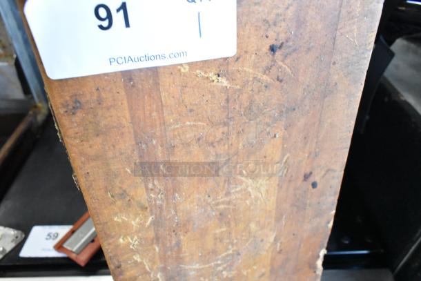 Wooden butcher block cutting board, worn condition with visible scratches and a tag labeled "91" from PCIAuctions.com.