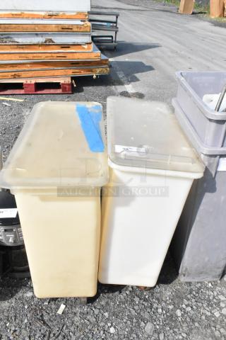 Two white poly ingredient bins on commercial casters, slightly worn, with lids. Ideal for commercial kitchen use.