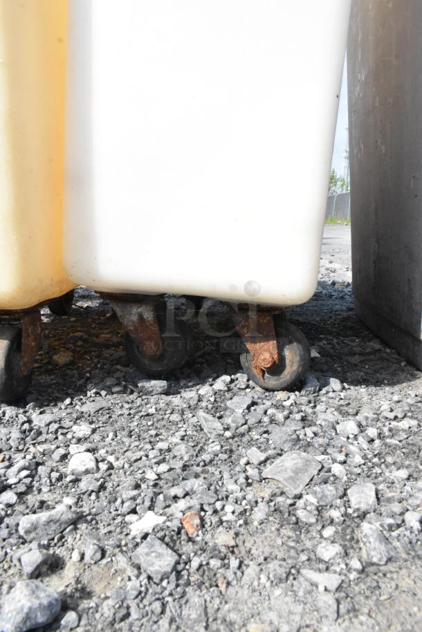 White poly ingredient bins on commercial casters, showing signs of wear. Suitable for storage and transport.