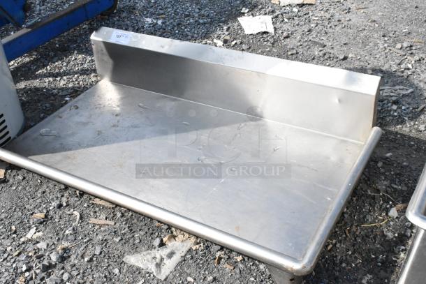 Stainless steel right side dishwasher table, lacks legs. Features raised back and side edges. Used condition, minor dents.