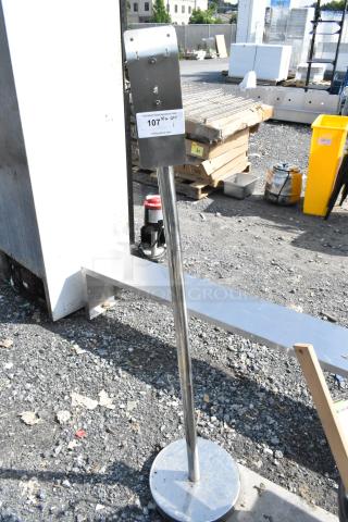 Metal stand with a round base, chrome finish, and a label indicating auction item 107. Suitable for various uses.