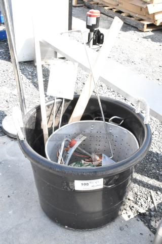 Black poly bin with mixed contents, including a metal steam stock pot, tools, and wooden pieces. Label marked "108" visible.