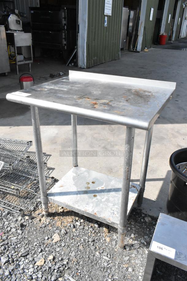 Stainless steel table with metal undershelf, some rust and surface wear, ideal for industrial or kitchen use.