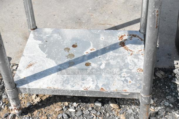 Stainless steel table with metal under shelf, showing rust and wear. Ideal for industrial or outdoor use.