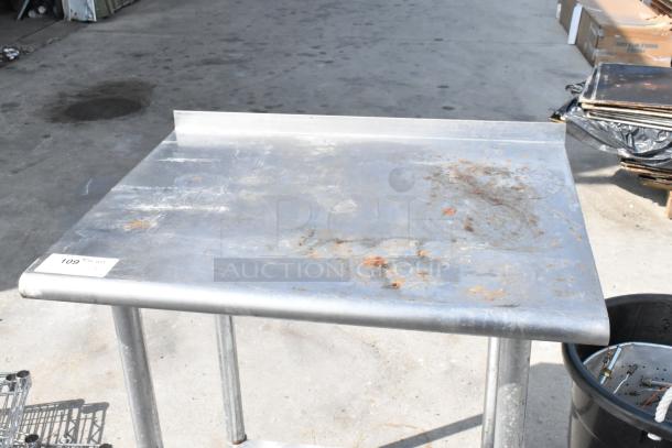 Stainless steel table with metal under shelf, showing signs of wear and rust, marked with item number 109.