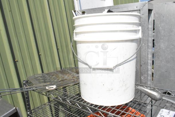 Chrome finish 5-tier wire shelving unit with visible wear, holding a white bucket. Buyer must dismantle for shipping.
