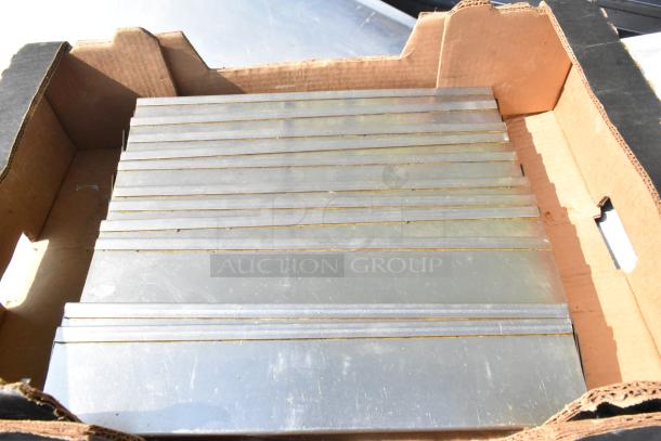 11 metal pieces in a cardboard box, each with uniform size and slight wear, indicating durability and utility.