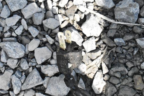 The image shows a damaged electrical plug on a gravel surface, not the specified auction item.