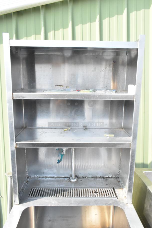 Stainless steel single bay sink with water dispenser, featuring two-tier over shelf and under shelf. Visible wear and stains.