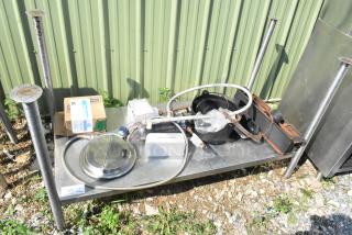 Metal under shelf with legs containing assorted plumbing and mechanical parts, includes a box labeled "Ice Machine," set outdoors.