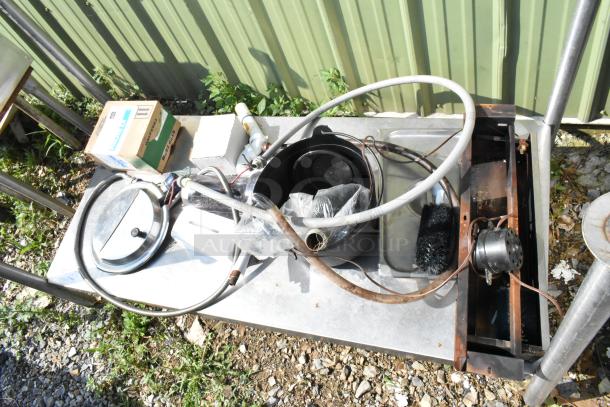 Metal under shelf with legs contains various items, including a hose, pots, and a cardboard box. Exterior use condition.