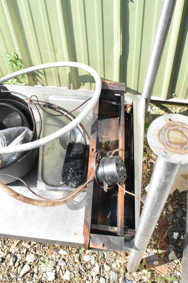 Metal under shelf with legs, includes assorted contents like a brush and metal items, in used condition.
