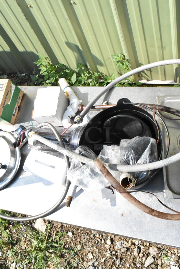 Metal under shelf with legs, includes various hoses, valves, and containers. Signs of wear, suitable for storage or workshop.