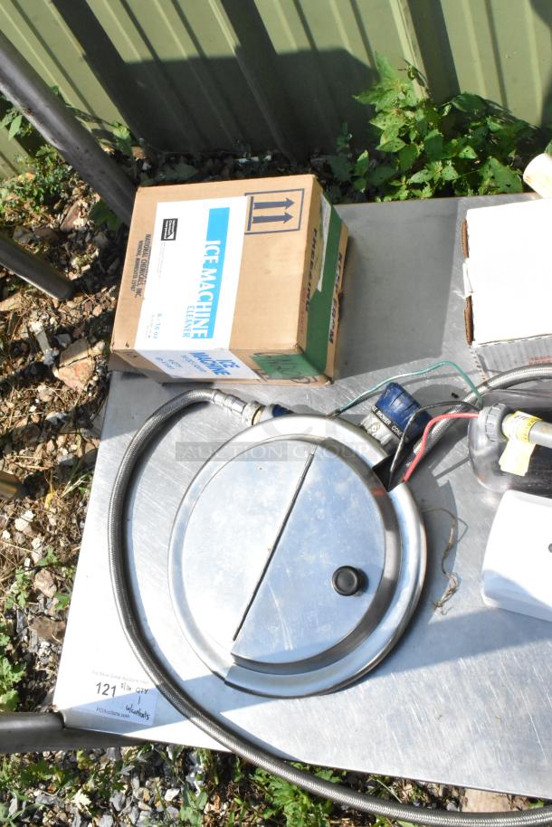 Metal under shelf with legs, includes circular lid, hoses, and boxes. Good condition with visible auction tag.