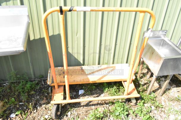 Orange metal cart on commercial casters, used condition, with a simple frame and handle, suitable for industrial use.