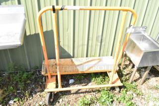 Orange metal cart on commercial casters, used condition, with a simple frame and handle, suitable for industrial use.