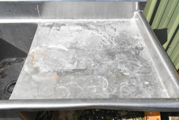 Marlo stainless steel 3 bay sink with dual drain boards, showing wear and surface scratches, highlighting the left drain board.