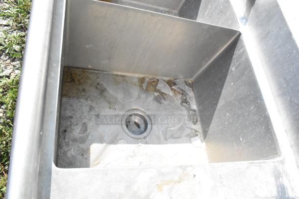 Marlo Stainless Steel 3-bay sink with dual drain boards, showing moderate wear and debris in basins, suitable for commercial use.