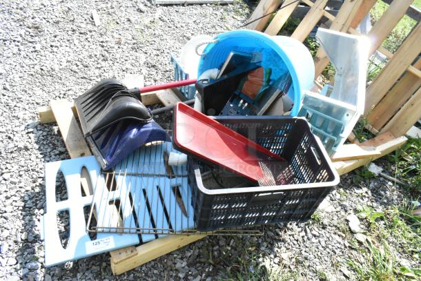 Pallet lot with snow shovels, poly bucket, metal shelf, and misc. items on gravel, outdoor setting.