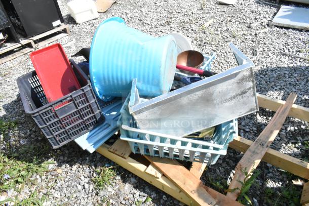 Pallet with assorted items including blue poly bucket, metal shelf, red snow shovels, and plastic crates. Outdoor setting.